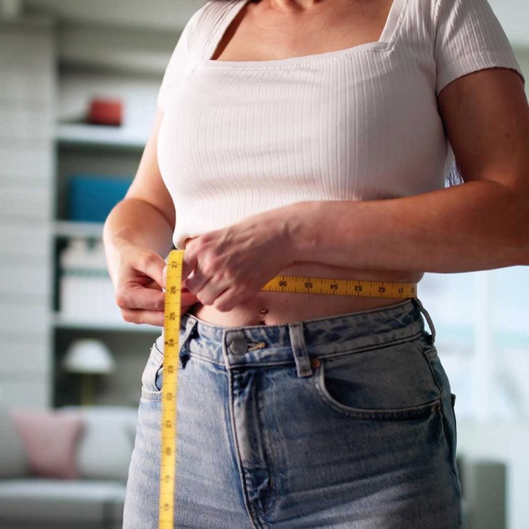 Wie man eine Diät wirklich durchhält Junge Frau misst Ihren Bauchumfang